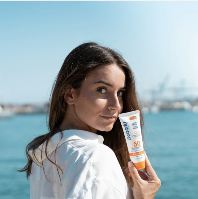 femme qui tient pot de crème solaire